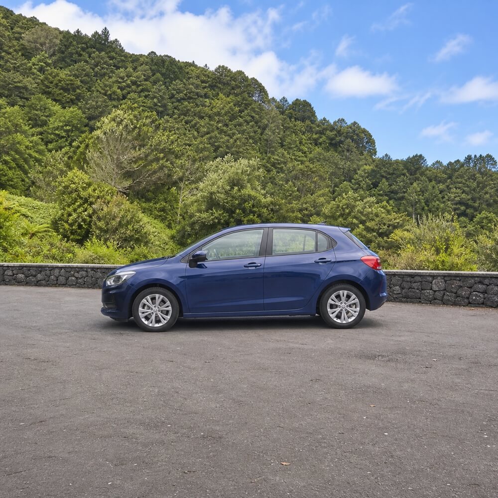 Voiture compacte bleue garée sur une aire pavée entourée de végétation à Madère